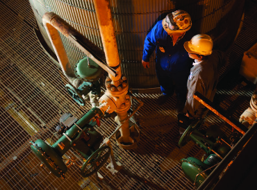 Two technicians inspecting a long-lasting Fisher control valve in operation, showcasing the durability and reliability of Fisher parts in demanding industrial environments.